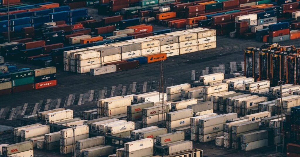 物流倉庫に山積みされた国際配送用の段ボール箱とコンテナ