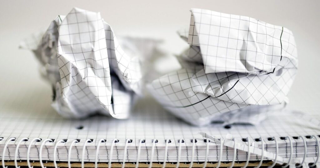 山積みの書類と丸められた紙くず、無駄な努力のメタファー