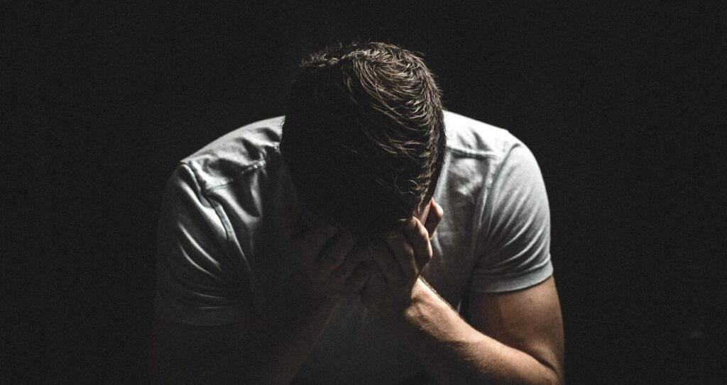 暗い部屋でPC画面に表示された「アカウント停止」の通知に打ちひしがれる男性