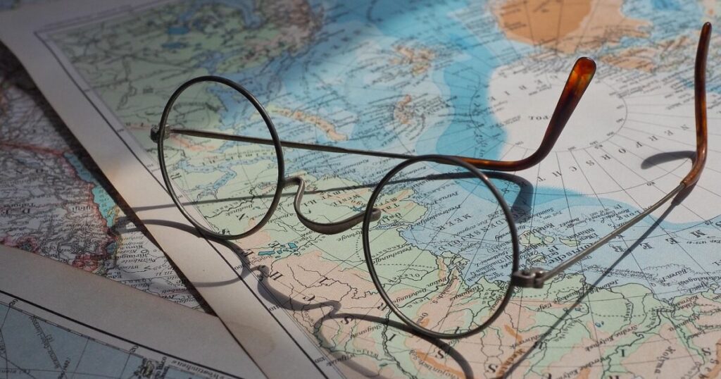 世界地図の上に置かれたコンパスとグローバル展開のイメージ